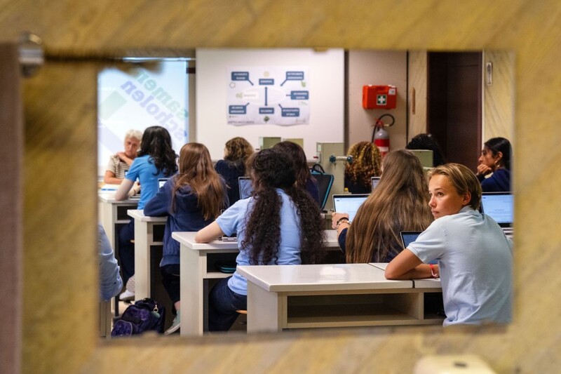 We zien leerlingen van eerste graad middelbaar in een klaslokaal, door de deur gezien.