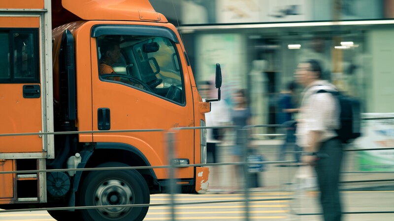 Oranje vrachtwagen rijdt door stadscentrum