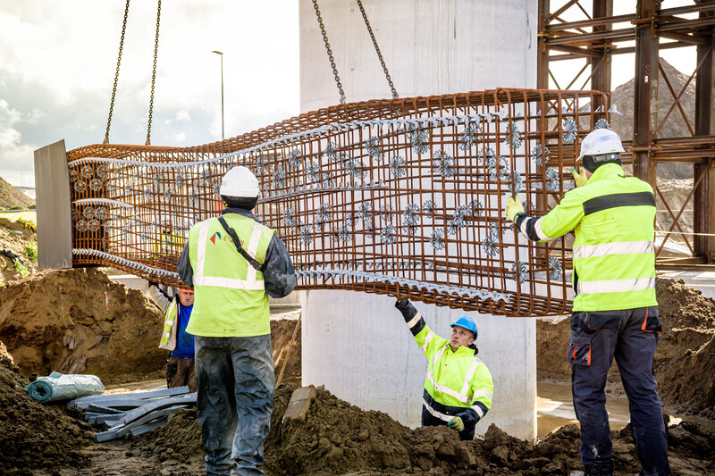 Arbeiders laten bewapening voor beton zakken op een bouwwerf