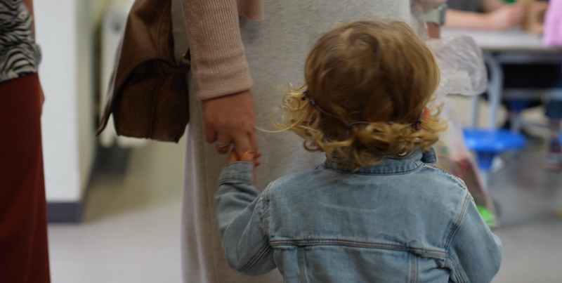 een kind wordt opgehaald door moeder in buitenschoolse kinderopvang