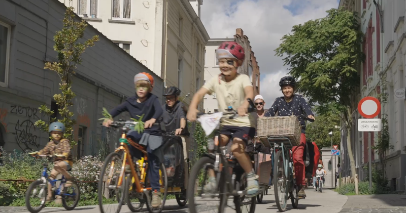 Kinderen fietsen op straat in een bonte parade