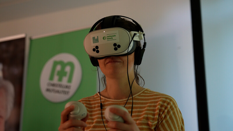 Vrouw heeft VR-bril op en controllers in handen