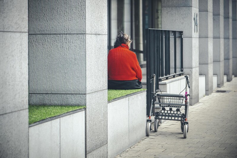 Vrouw zit neer op vensterbank naast rollator