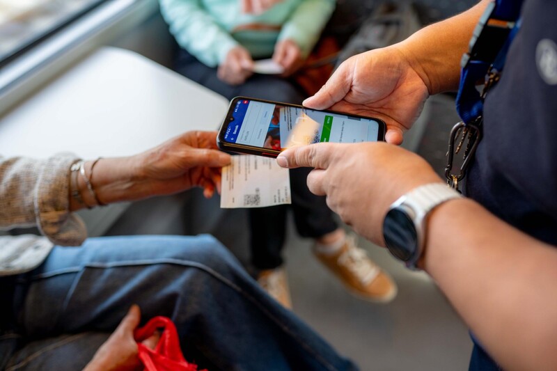 Een treinbegeleider controleert een ticket van een reiziger.