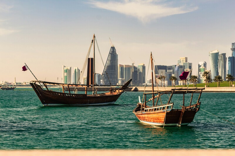 Skyline van Doha, met daarvoor twee houten vissersboten in de zee